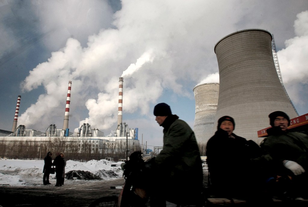 Files/The Associated Press Workers cycle past a coal-fired power plant on a tricycle cart in Changchun in northeast Chinas Jilin province. Chinas label as a developing nation in climate matters is facing a challenge. ---